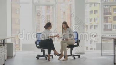 一名妇女解释说，办公室工作人员坐着两名年轻妇女坐在办公室椅子上谈判公司的文件